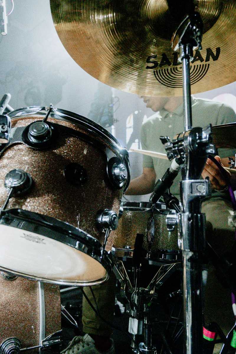 A man behind a drumkit, obscured by cymbals